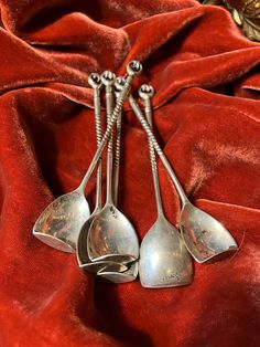 three silver spoons sitting on top of a red cloth