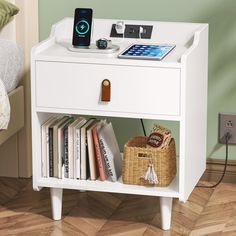 a white nightstand with books and an electronic device on top