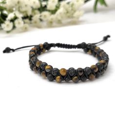 ✦Gemstone: Yellow Tigereye / Lava ✦Color: Yellow / Black ✦Shape: Round  ✦Bead Size: 4mm  ✦QTY: 1 pc / package Description: Elevate your spiritual journey and energy with our handcrafted Macrame Double Layer Beaded Bracelet. This unique piece combines the power of 4mm yellow tigereye and lava beads, offering spiritual protection and balance. Experience the beauty of natural gemstones and their harmonious energies. Gemstone Properties: Yellow tigereye is known for its ability to enhance focus, courage, and personal power, while lava stone provides grounding and stability. Together, they create a powerful blend of energies that promote inner strength and resilience. Double Layer Design: The double layer design symbolizes layered spiritual protection and balance. Macrame Closure: The adjustabl Adjustable Lava Stone Beaded Bracelets With Natural Stones, Bohemian Black Braided Bracelet With 8mm Beads, Black Bohemian Braided Bracelet With 8mm Beads, Adjustable Hand-strung Lava Stone Bracelet, Adjustable Hand-strung Lava Stone Jewelry, Handmade Adjustable Lava Stone Beaded Bracelets, Adjustable Lava Stone Bracelets With Gemstone Beads, Adjustable Lava Stone Bracelet With Gemstone Beads, Adjustable Lava Stone Bead Jewelry