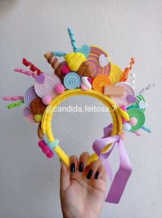 a hand holding up a hair accessory made out of candy and lollipops