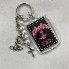 a keychain with a cross and pearls attached to it, sitting on a white surface