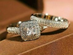 two wedding rings sitting on top of a brown velvet cushioned surface with diamonds in the middle