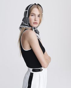 a woman wearing a black and white scarf over her head is posing for the camera