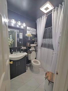 a white toilet sitting in a bathroom next to a sink and shower curtained window