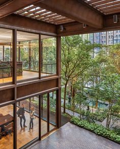 the inside of an office building with glass walls and wood flooring, looking out onto a courtyard