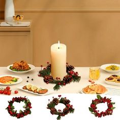 the table is set for christmas dinner with candles, plates and wreaths on it