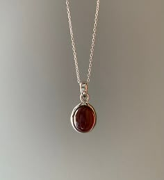 Sterling silver garnet necklace. This beautiful deep red garnet comes in a circular shape and set in an elegant silver design. Garnet is a deeply spiritual stone that inspires love and devotion. It comes on an 18 inch silver chain. Gift box available for purchase. Search GIFTBOX Simple Garnet Jewelry Set, Red Necklace Stone, Red Pendant Silver Necklace, Garnet Jewelry Necklace, Necklace Delicate, Garnet Necklace, Dope Jewelry, Silver Design, Charity Shop