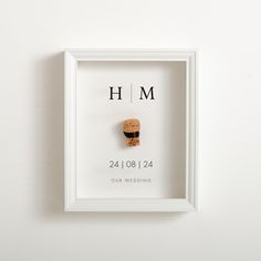 a white frame with a cork in it and the word h m printed on it