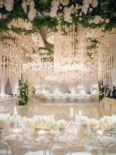 an elegant wedding reception setup with white flowers and chandelier hanging from the ceiling