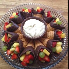 a glass plate topped with fruit and chocolate covered pastries on top of a wooden table