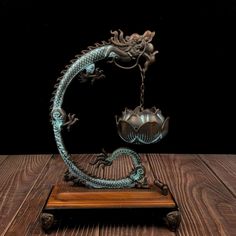 a metal dragon sculpture sitting on top of a wooden table