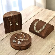 three pieces of jewelry sitting on top of a wooden table next to a box with two necklaces