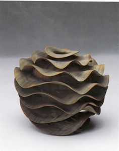 a wooden bowl with wavy designs on the top and bottom, sitting on a white surface