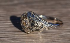 an antique style diamond ring sitting on top of a wooden table