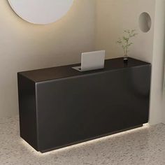 a laptop computer sitting on top of a black cabinet next to a white wall and round mirror