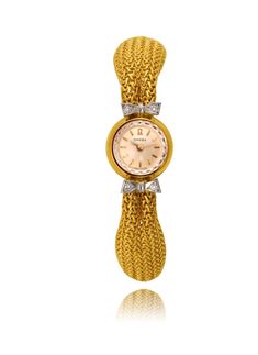 This lady's Swiss made Omega wristwatch is crafted in 18K yellow gold and has a 15mm case diameter. It displays a round shaped champagne colour dial and gold stick hour markers and hands with a crown on the back of the case. The Omega logo is at the 12 o'clock and it carries a manual winding movement. The watch is attached to an 18K yellow gold tapered loose mesh link bracelet with a fold-over clasp. Two 18K white gold bow shaped designs are attached to the band as they frame the dial and they a Evening Yellow Gold Diamond Watch, Gold Evening Watch With Jubilee Bracelet, Gold Diamond Watch For Evening, Yellow Gold Diamond Watch With Metal Dial For Formal, Yellow Gold Watch With Round Dial For Evening, Gold Diamond Watch With Metal Dial For Evening, Yellow Gold Watches With Gold Clasp For Evening, Gold Evening Jewelry And Watches With Round Dial, Gold Jewelry And Watches With Round Dial For Evening