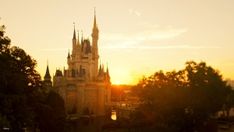 the sun is setting in front of a castle