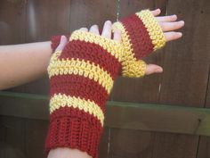 a woman's hand wearing red and yellow crocheted arm warmers