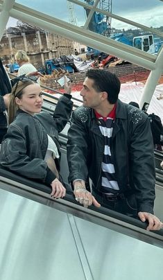 a man and woman sitting on an escalator looking at each other while one holds his hand out