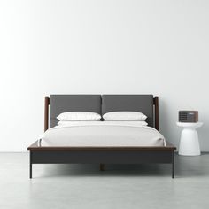 a bed sitting next to a night stand on top of a white floor in front of a wall