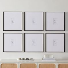 four white framed pictures hang on the wall above a dresser and sideboard in a modern living room