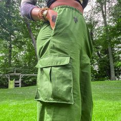 a person standing in the grass with their hands on their hips and wearing green pants