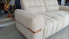 a white couch sitting in a garage next to a wall with tools on top of it