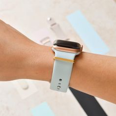 an apple watch on someone's arm with a gold and blue band, showing the time