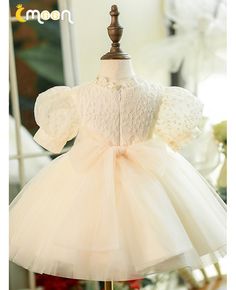 a white dress on a mannequin stand in front of a mirror with flowers