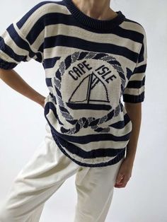 Lovely short sleeve knit sweater with a crewneck and cable knit details at the hems. The knit reads Cape Isle at the front and depicts a sailboat as well. Perfect navy and ivory stripes. Tag reads Cape Isle Knitters Made in USA Dime size discoloration at the left front shoulder. Navy Cable Knit Crew Neck Top, Striped Knit Sweater With Short Sleeves, Nautical Cotton Sweater With Crew Neck, Nautical Cotton Crew Neck Sweater, Vintage Cable Knit Crew Neck Top, Short Sleeve Knit Sweater, Vintage Cape, Knit Outerwear, Line Shopping