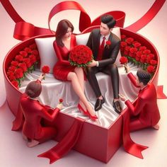 a man and woman sitting on top of a heart shaped box filled with red roses