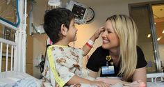 a woman talking to a child in a hospital bed with medical equipment on the wall behind her