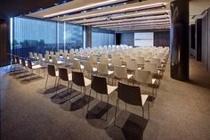 an empty conference room with rows of chairs in front of a large window at night