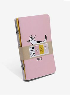 a pink notebook with a black and white cat drawn on the front cover is shown