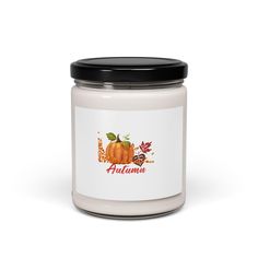 an autumn candle with pumpkins and leaves on the label, sitting in front of a white background