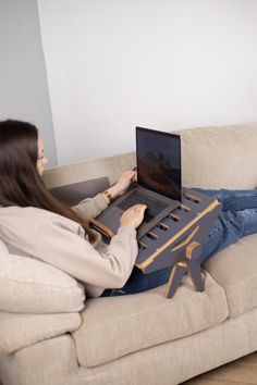 a woman sitting on a couch using a laptop computer