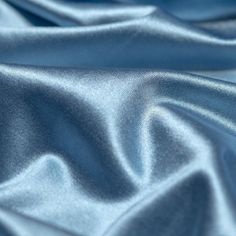 a close up view of a blue satin fabric with very soft folds and wrinkles