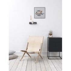 a chair sitting in the middle of a room next to a dresser and pillow on the floor