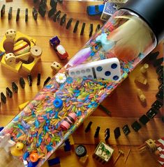 a bottle filled with lots of different colored confetti next to other items on a table