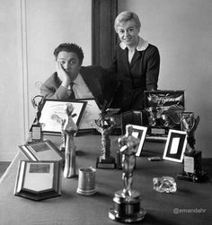 two women are sitting at a table with trophies and plaques on it, posing for the camera