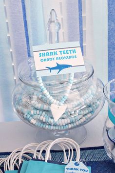 there is a shark teeth candy bowl on the table with blue and white decorations around it