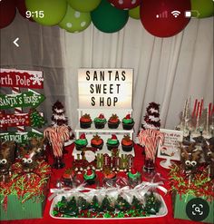 a christmas themed dessert table with santa's sweet shop sign in the background and candy