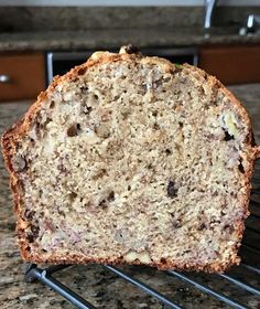 a loaf of banana bread sitting on top of a metal rack next to a counter