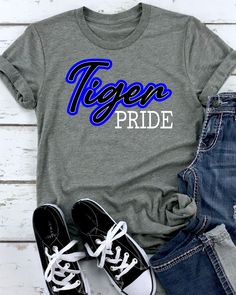 Designed with the ultimate Tigers fan in mind, this heat transfer features a bold and vibrant colors in a simple design. Made with high-quality direct to film, this heat press transfer is perfect for wearing to games, tailgates, or just around town. Show off your school spirit and support your favorite team by sporting the Tiger Pride heat transfer on any color tshirt you want to apply it on. It's the perfect way to show off your love for your school and your dedication to the Tigers. Don't wait Black Cotton Sublimation Design For Game Day, Black School Spirit Sublimation Design For Fan Gear, Black Sublimation T-shirt With Letter Print For Fans, Black T-shirt With Heat Transfer Vinyl For Sports Season, Blue Sublimation Design Shirt With Graphic Print For Fans, Blue Graphic Print Sublimation Fan Gear, Blue Graphic Print Sublimation Design For Fan Gear, Blue School Spirit Sublimation T-shirt With Graphic Print, Collegiate Sublimation Design For Fan Merchandise