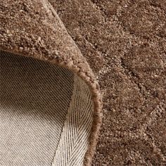 a close up view of the corner of a brown rug with an area rug underneath it