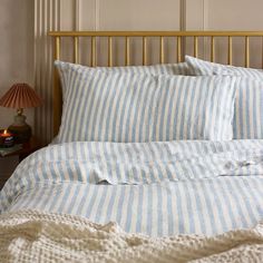 a bed with blue and white striped sheets in a bedroom next to a night stand