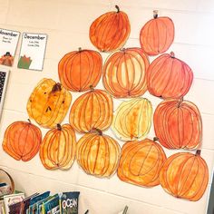 a bulletin board with pumpkins hanging from it's sides and books on the floor