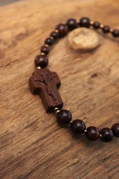 +.This is a rosary bracelet made of wood. The crucifix and the beads are constructed of wood. +.The wooden rosary is beneficial because you can feel the softness of the wood while praying. The more you contact wood, the more it takes on a natural brilliance. +.Surinamese ebony was used to make the crucifix. The light brown tone of Surinamese ebony is appealing. Surinamese ebony is so hard that it may be carved finely. It is carved over a long period of time rather than molded for a few minutes. Adjustable Hand-strung Rosary As Gift, Brown Crucifix Jewelry For Gifts, Brown Crucifix Jewelry Gift, Spiritual Rosary Bracelet As Gift, Spiritual Cross Bracelets As Gifts, Adjustable Spiritual Rosary As Gift, Spiritual Brown Rosary Bracelet For Gift, Brown Cross Bracelet Spiritual Style, Spiritual Brown Cross Bracelet