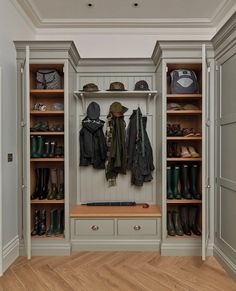 a walk in closet filled with lots of shoes and coats on top of wooden shelves