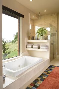 a bathroom with a large bathtub next to a window and a rug on the floor